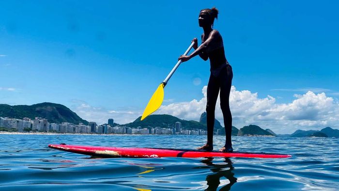 A woman balancing on a paddleboard while rowing