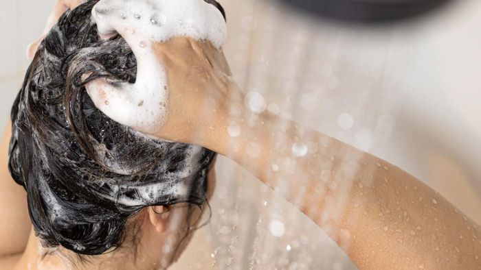 Woman applying shampoo to her hair in the shower