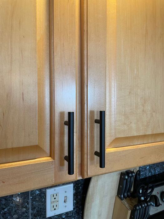 Close-up view of a kitchen cabinet featuring sleek matte black cabinet pulls.