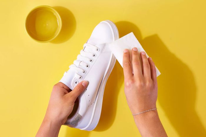 Magic eraser gently scrubbing the surface of white leather shoes