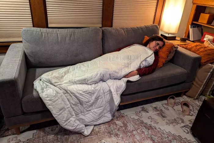 A person resting on a couch covered with the Aricove Cooling Weighted Blanket