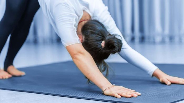 A female practicing the downward dog yoga pose on a vibrant blue mat