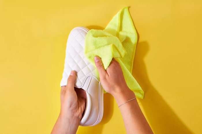 Microfiber cloth being used to clean the side of a white leather shoe
