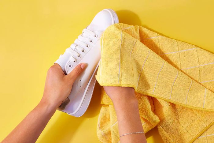 Microfiber towel being used to wipe down a white leather shoe
