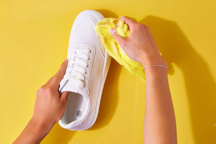 Sudsy cloth being used to clean white leather shoes
