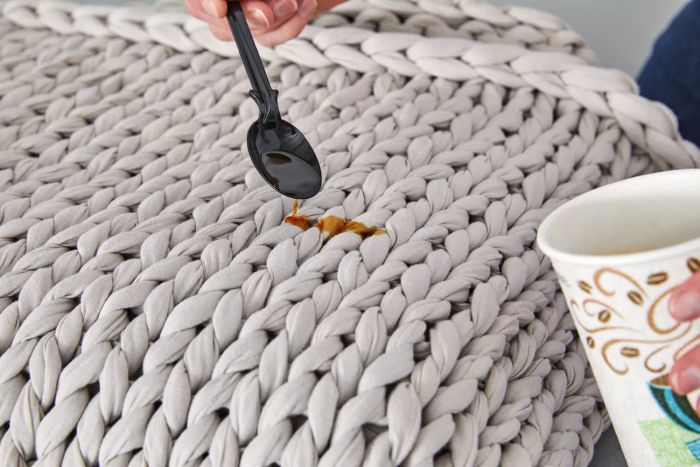 A hand pouring coffee onto a Bearaby Cotton Weighted Blanket using a spoon