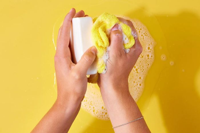 Bar soap generating suds on a yellow microfiber cloth