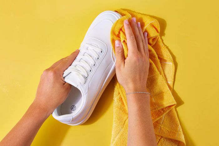 Damp cloth removing dirt from a white leather shoe