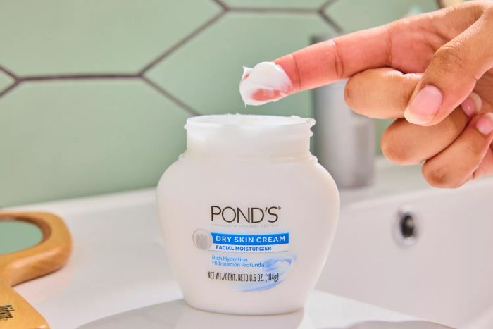 A person with Pond's Dry Skin Cream Facial Moisturizer on their fingertip