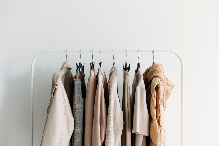 A clothing rack displaying a variety of neutral-toned jackets and coats neatly arranged.