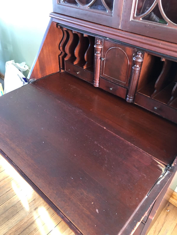 After image of the desk restored to its original dark wood finish