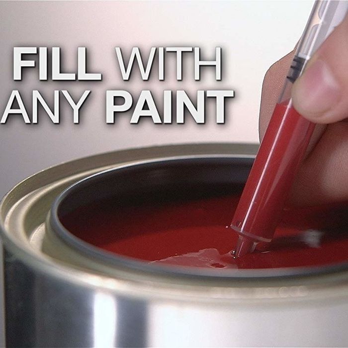 A hand filling a syringe-like pen from a paint bucket