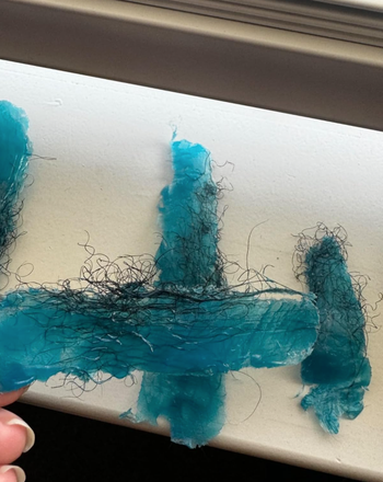 A close-up of the reviewer’s blue wax strips, now covered in removed hair