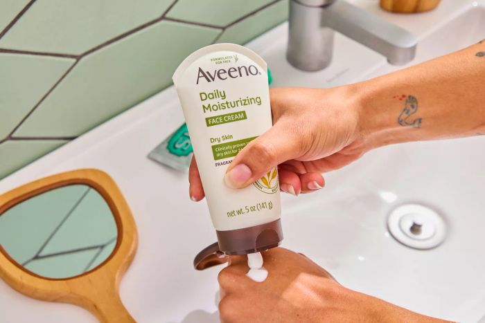 A person applying the Aveeno Daily Moisturizing Face Cream to the back of their hand