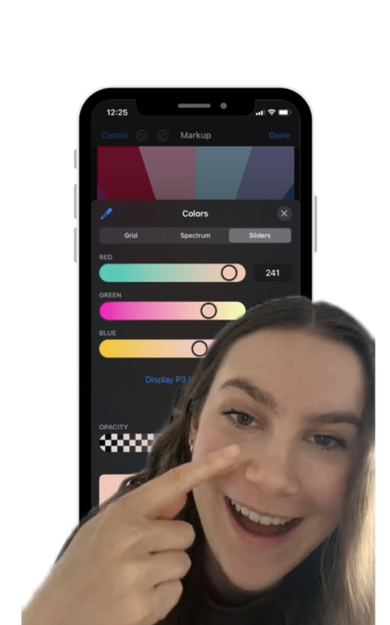 A woman smiles and points to her cheek, with a phone screen in the background displaying a color selection tool in a drawing app.