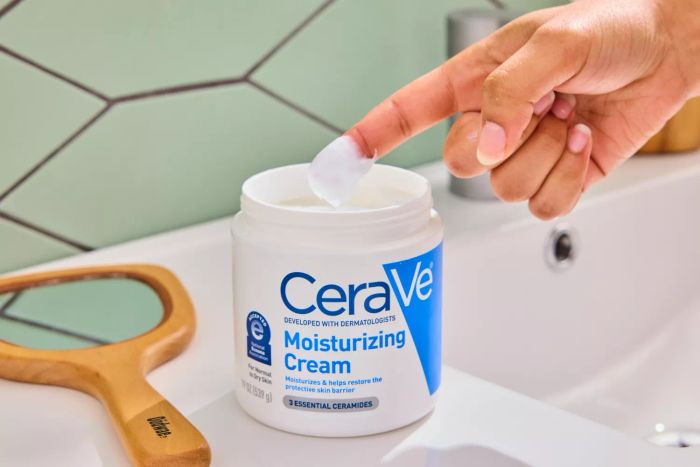 A person dipping their finger into the CeraVe Moisturizing Cream