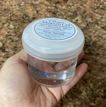 A reviewer holding the jar of clear adhesive gel