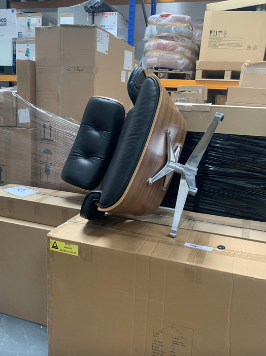 An office chair tipped over on its side, surrounded by cardboard boxes in a warehouse environment