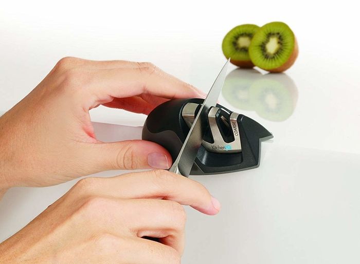 Hands sliding a knife through the compact sharpener