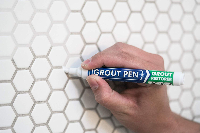 A model using a small pen to restore grout to its bright white color