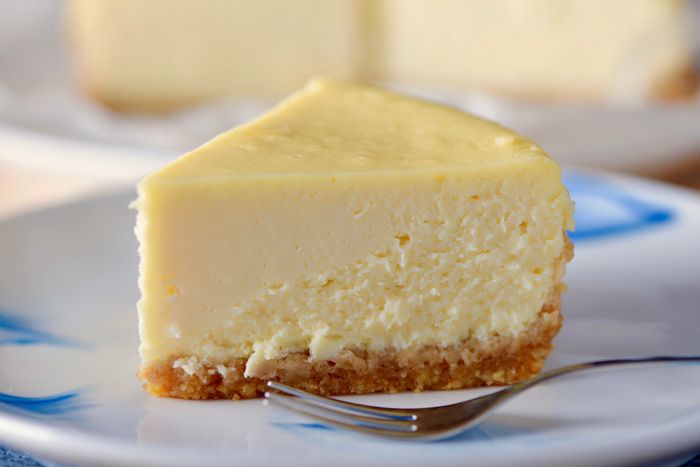 A close-up of a slice of cheesecake with a fork ready to dig in.