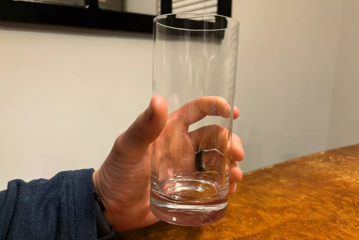 A person holding up a glass from the Luigi Bormioli Set of 4 Classico Tall Beverage Set