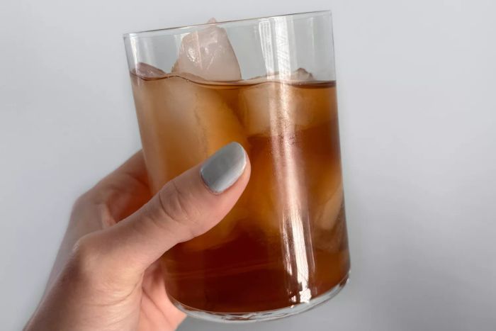 A person holding a Made In Drinking Glass filled with iced tea
