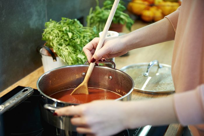 A person preparing tomato soup in a kitchen.