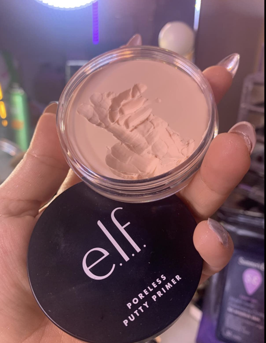 A reviewer holding the tin of beige-colored primer