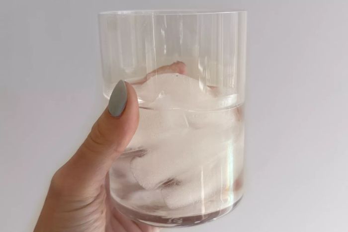 A person holding a Made In Drinking Glass filled with ice water
