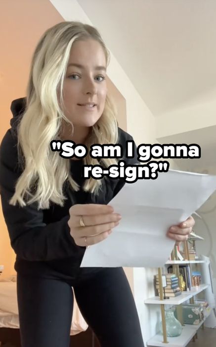 A person holding papers with a bookshelf visible in the background
