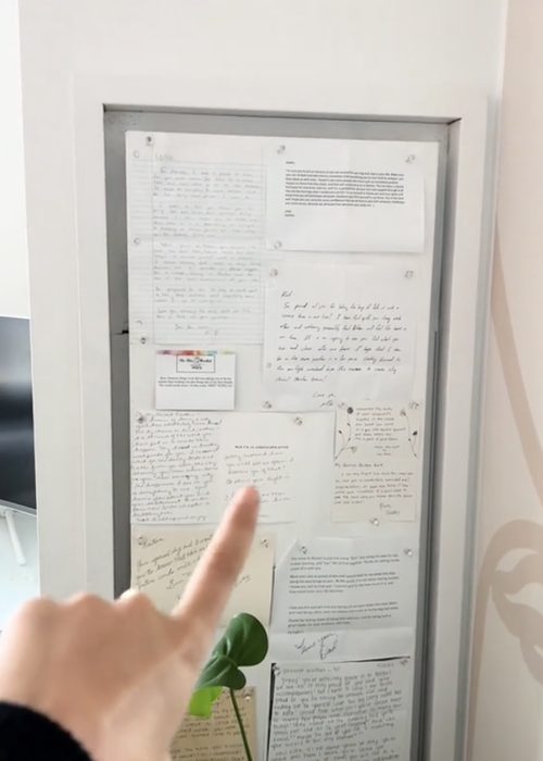 A door adorned with handwritten notes, with a person pointing to them