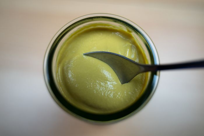 A spoonful of yellow mustard scooped from a jar.