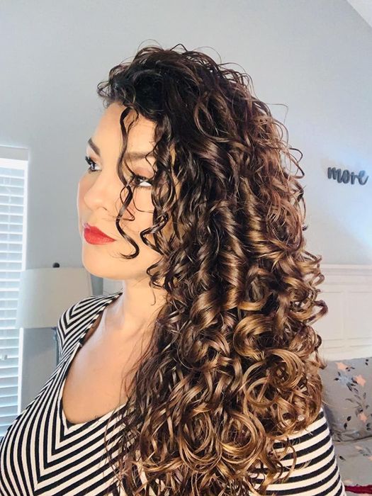 A reviewer showcasing soft, shiny curls after using the hair treatment