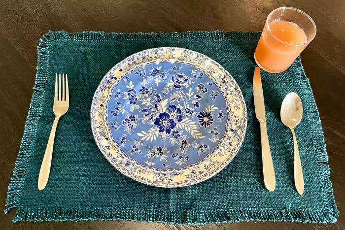 A Bormioli Rocco Bodega Collection Glassware filled with orange liquid, placed on a table alongside silverware and a vibrant plate