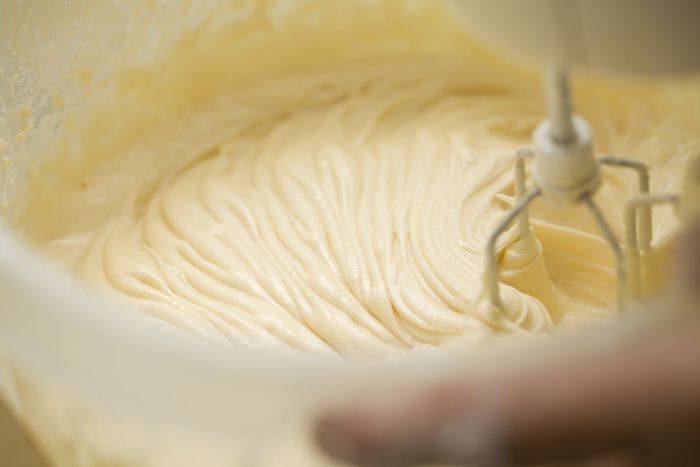 A close-up shot of someone using an electric hand mixer to blend cake batter.