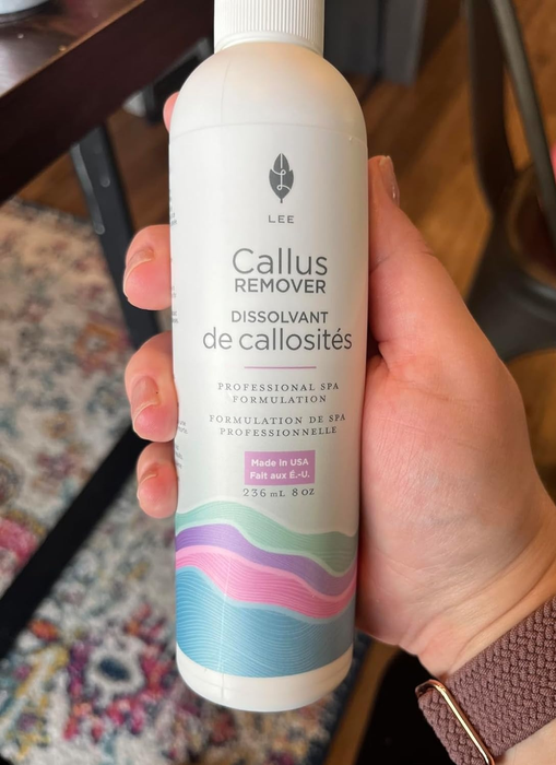 A hand holding a bottle of Lee Callus Remover, showcasing the product