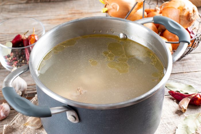 A saucepan filled with simmering chicken broth.