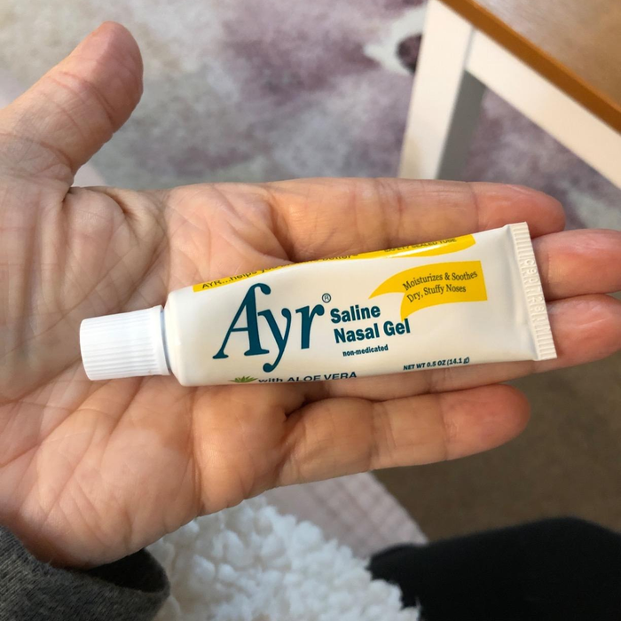 A small tube of nasal gel resting in the palm of a reviewer's hand