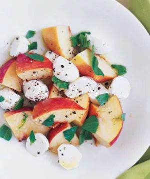 Peach, mozzarella, and basil salad on a white background.