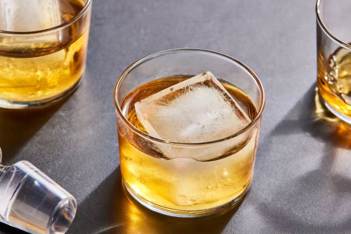 A Bormioli Rocco Bodega Mini 7.5-Ounce Glass Tumbler Set glass containing an ice cube and yellow liquid