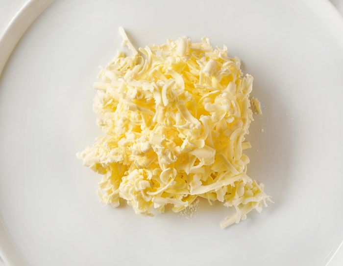 Cold grated butter neatly arranged on a white plate.