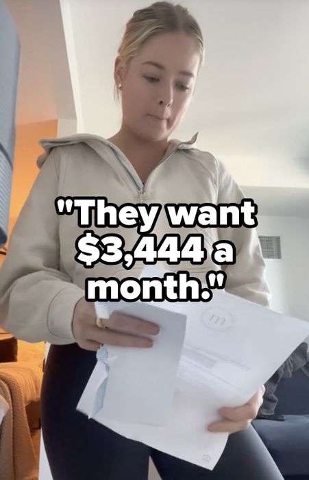 A woman holding papers, wearing a light zippered jacket