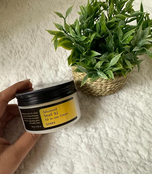 A reviewer holding the jar of Cosrx Snail Mucin 92% Moisturizer