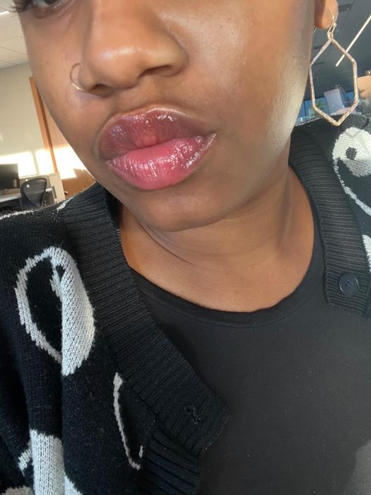 A reviewer modeling the lip oil, displaying its natural finish