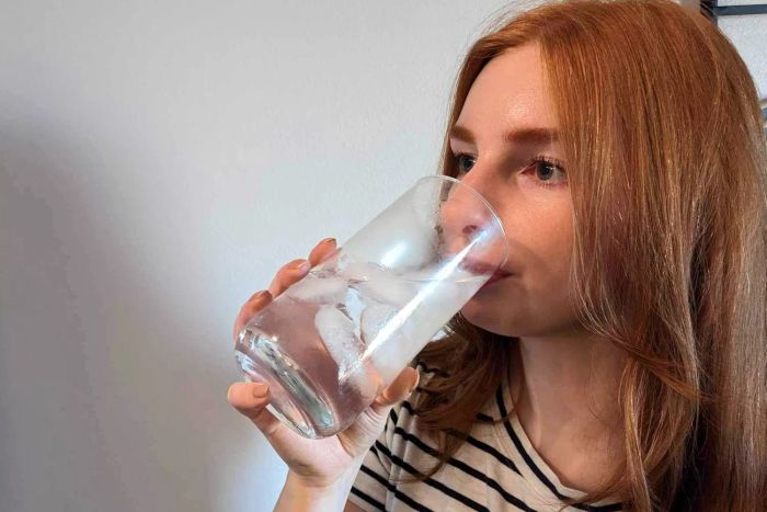 A person enjoying ice water from a Libbey Ascent 16-Piece Assorted Glassware Set glass