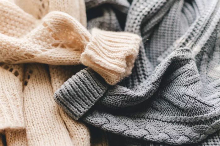 A close-up of knitted grey and beige sweaters or scarves showcasing their textured fabric.