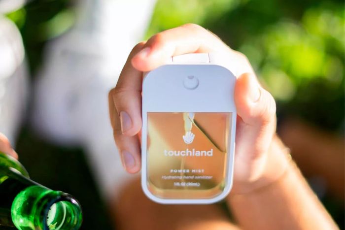A person holding the Touchland Power Mist Hydrating Hand Sanitizer Spray, Fresh 3-Pack