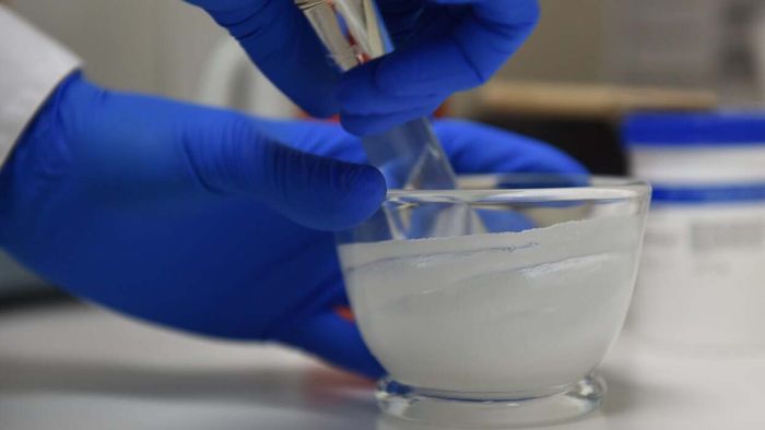 A compounding pharmacist, gloved and focused, mixes medications tailored to individual prescriptions, ensuring the correct formulation for each patient's needs.