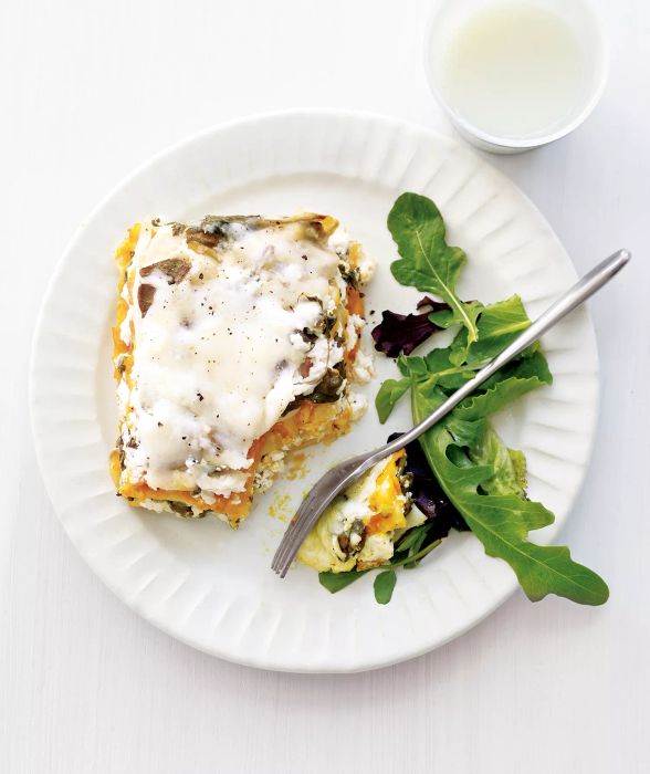 Slow-Cooker Squash Lasagna Topped With Cheese on a Plate Next to a Few Lettuce Leaves